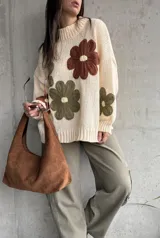 Sweater de tejido de punto color natural, con diseño de flores grandes aplicadas en tonos marrón y verde oliva. Presenta cuello redondo, mangas largas y corte holgado.