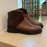 Bota corta de cuero color marrón con detalle de cuero con textura de cocodrilo en la parte trasera y panel de gamuza en el lateral. Tiene cierre en el lateral interno y suela de goma negra.