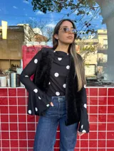 Blusa negra con estampado de lunares blancos, de corte ajustado al cuerpo, cuello redondo y mangas largas con terminación acampanada.