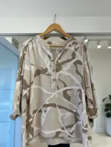 Camisa de lino con estampado batik en tonos beige y marrón, cuello en V con solapa corta y tres botones frontales, y mangas largas.