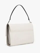 Cartera shoulder de Tommy Hilfiger en color beige, con solapa y correa corta ajustable de color negro. Presenta el monograma "TH" en relieve negro en el frente y herrajes metálicos plateados.