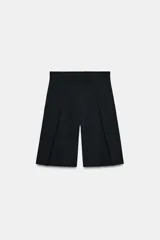 Bermudas de tiro alto color negro, con detalle de pliegues marcados en el delantero y cierre frontal con cremallera y ganchos metálicos.