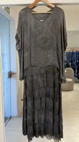 Vestido midi gris de efecto gastado, con escote redondo, mangas cortas amplias y falda con múltiples volados superpuestos de terminaciones deshilachadas.