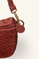 Bandolera de gamuza color marrón con diseño de media luna, decorada con tachas metálicas doradas distribuidas en el frente. Cuenta con cierre superior metálico y correa larga ajustable para llevar cruzada.