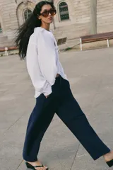 Pantalón barrel color azul marino, de tiro bajo, pernera holgada con diseño redondeado que se estrecha hacia el tobillo, con bolsillos delanteros y cierre frontal.