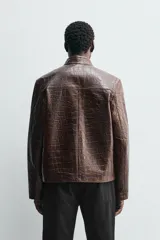 Cazadora de corte regular fit confeccionada en piel con textura grabada efecto cocodrilo. Presenta cuello subido, manga larga, cierre frontal de cremallera y bolsillos laterales de vivo.