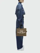 Bolso tote mediano de lona color celeste con estampado frontal del logo "The Tote Bag" en blanco y el nombre de la marca "Marc Jacobs" en la parte inferior. Tiene doble asa de mano y correa de hombro ajustable y extraíble.