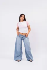 Jeans wide leg de denim rígido en lavado celeste vintage, con diseño de cintura cruzada y cierre asimétrico de doble botón.