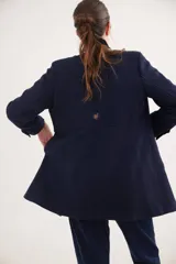 Tapado corto de paño de lana en color celeste, con cuello mao en pana marrón, botones forrados en contraste y cinta de terciopelo aplicada. Presenta una silueta entallada con bolsillos delanteros.