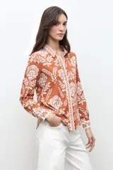 Camisa de manga larga con estampado floral en tonos ladrillo y blanco, con cuello camisero y cierre frontal de botones.