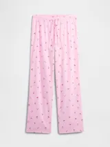 Pijama de dos piezas confeccionado en popelina, compuesto por una camisa de manga corta con cuello solapa y cierre frontal de botones, y un pantalón largo de corte recto con cintura elástica. Presenta un estampado integral de cerezas sobre fondo rosado.