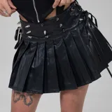 Minifalda negra de cuero sintético con tablas y detalles de remaches metálicos.