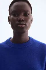 Remera de punto de color azul eléctrico, con cuello redondo y mangas cortas amplias. Presenta un calce holgado y textura suave.