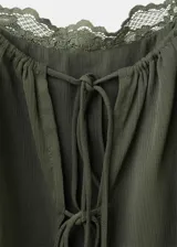 Vestido corto verde militar de diseño recto, con escote recto, tirantes finos y volantes en capas. Cuenta con forro interior.