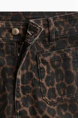 Jean de denim con tiro alto, corte ajustado hasta la rodilla y diseño acampanado, con estampado animal print tipo leopardo. Cuenta con bolsillos de parche delanteros y trabillas para cinturón.