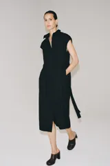 Vestido midi camisero de algodón color negro, con cuello solapa, sin mangas y cierre frontal con botones ocultos por solapa. Incluye cintura ajustable con tiras de lazada lateral en el mismo tejido.