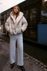 Anorak corto acolchado de Zara, color beige, con cuello subido, capucha, manga larga con puños elásticos y cierre frontal cruzado con botones magnéticos.