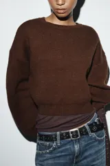 Jersey de punto liso con cuello redondo, manga larga y diseño de hombros caídos.