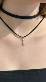 Gargantilla doble tipo choker de gamuza negra, con un dije metálico plateado en forma de estrella fugaz.