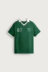 Polo de fútbol retro color verde oscuro, de corte regular fit, con cuello solapa blanco, mangas cortas con ribetes blancos y bandas en los hombros. Cuenta con estampado frontal del número 80 y un gráfico con efecto lavado.