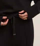 Pantalón wide leg de punto con textura acanalada, cintura elástica con lazo ajustable y detalles metalizados, y frisos verticales a lo largo de la pierna.