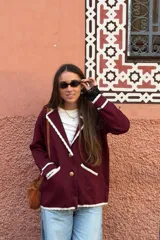Blazer tejido de punto en color bordó con detalles de terminaciones en color crema con diseño de ondas en solapas, bolsillos y ruedo. Presenta cierre frontal con botones dorados de estilo vintage.