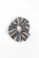 Scrunchie para el pelo de diseño fruncido, confeccionada en tela gris con patrón de rayas verticales en tonos blancos y mostaza.