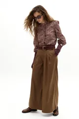 Pantalón culotte color camel con sutiles rayas bordó, de cintura alta y reforzada, con pinzas en la cintura, cierre frontal con gancho y botón interno, y bolsillos laterales. Las piernas son anchas.