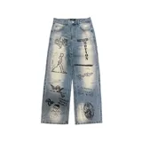 Pantalón de jean azul claro de corte ancho, con múltiples estampados artísticos estilo gráfico en color negro.