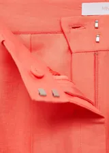 Pantalon de corte wideleg color naranja, confeccionado en mezcla de lino y lyocell. Presenta diseño de tiro alto con trabillas para cinturón, pinzas frontales, dos bolsillos laterales y dos bolsillos de ribete en la parte posterior. Cierre oculto de botón, gancho y cremallera.