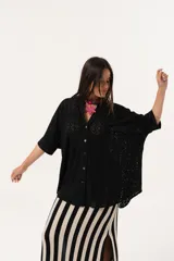Camisa negra de tejido calado, con escote en V, abotonada y manga 3/4.
