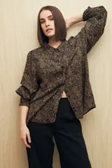 Camisa blanca con estampado lineal irregular en negro, de calce relajado, cuello clásico, abotonadura frontal y mangas largas con puños elastizados.