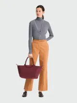 Bolso de mano tipo tote de la línea Le Pliage One de Longchamp, en color bordó. Presenta un diseño minimalista con cierre de cremallera superior, solapa con botón a presión y asas cortas de cuero.