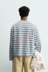 Camiseta de manga larga con corte relajado, cuello redondo y diseño de rayas horizontales en tonos azul claro, verde oscuro y naranja.