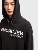 Sudadera con capucha Moncler Grenoble negra con estampado frontal de hashtag y texto invertido.