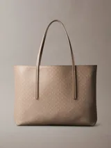 Cartera tote de Calvin Klein en color beige, con estampado de monograma CK repetido en toda la superficie, doble asa fija y diseño estructurado.