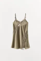 Vestido corto de satén con escote en pico y tirantes finos. Presenta delicadas aplicaciones de encaje a tono en el escote y a lo largo de la falda, con una abertura lateral en el bajo.