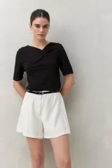 Remera blanca de manga corta con escote asimétrico y detalle de nudo con frunces en el centro del busto.