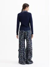 Pantalón de corte wide leg con diseño cargo, confeccionado en guipiure de denim azul con estampado floral. Presenta bolsillos laterales tipo cargo y cierre frontal.