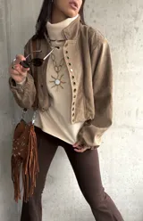 Polera de tejido de punto color beige, con cuello alto, mangas largas y aberturas laterales en el ruedo.
