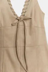 Vestido corto de estilo western con cuello halter y escote en pico con lazada frontal. Presenta un diseño ajustado en el torso y un bajo asimétrico decorado con flecos largos.