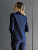 Blazer de tencel color azul marino con cuello de solapa y cierre frontal de un solo botón. Presenta bolsillos delanteros simulados con detalle de vivo trenzado y un diseño estructurado de calce entallado.
