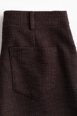 Pantalón amplio de punto bouclé color marrón oscuro, de tiro alto con elástico oculto en la cintura, bolsillos delanteros y cierre con botón.