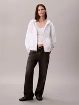 Buzo Calvin Klein de color blanco, con capucha ajustable mediante cordones, cierre frontal con cremallera y bolsillos tipo canguro. Presenta mangas largas y logo bordado en el pecho.