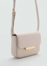 Bandolera color crema con correa ajustable, solapa con cierre metálico dorado y triple compartimento interno.
