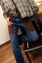 Jean de corte recto y tiro medio, confeccionado en denim celeste con inserciones de cuero marrón en las piernas que simulan chaparreras.