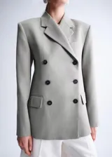 Blazer cruzado de lino y algodón color verde militar, con cuello solapa, hombreras marcadas, bolsillos con solapa y cierre de doble botonadura.