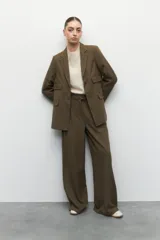 Blazer gris oscuro de corte clásico, con solapas de muesca, cierre con dos botones a tono, bolsillos de solapa decorativos y mangas largas.