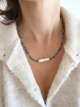 Collar corto de cuentas verdes con una perla de río alargada en el centro.