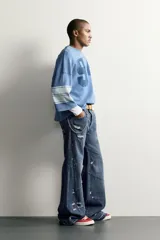 Jeans flare fit de denim azul oscuro con roturas y costuras decorativas en las perneras. Tiro medio y diseño de cinco bolsillos.
